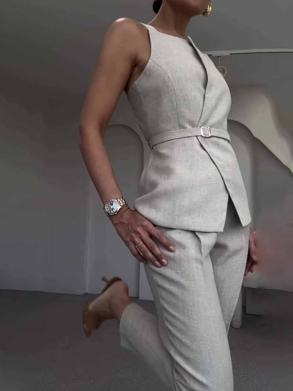 Woman wearing a light gray suit with a belt in a minimalistic setting